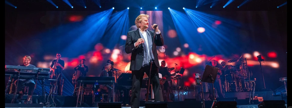 Ein Mann auf einer Bühne mit seiner Band im Hintergrund