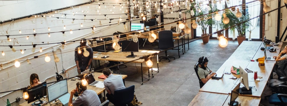 Menschen arbeiten in einem großen Raum nebeneinander