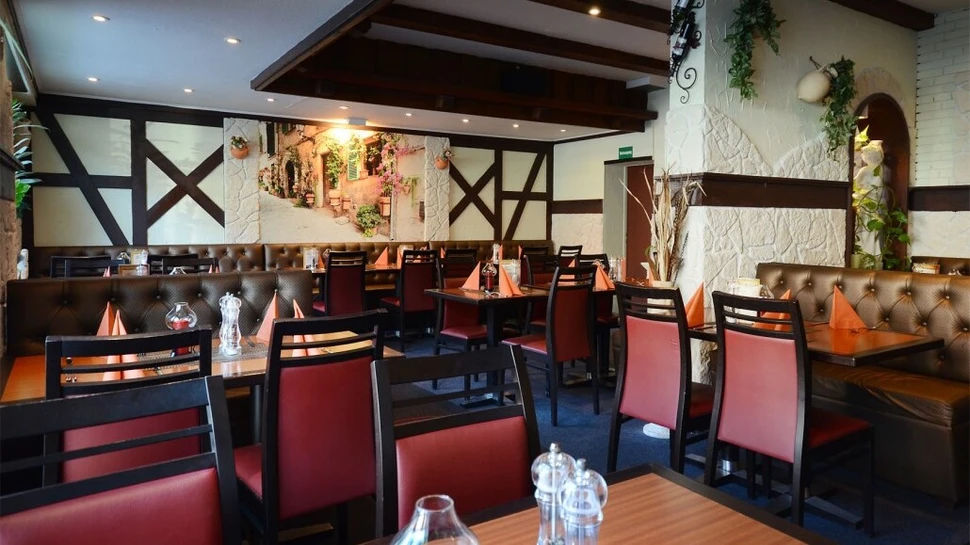 Das Restaurant Kreta von Innen Ein Raum mit Holzoptik sowie roten Stühlen und hölzernen Tischen
