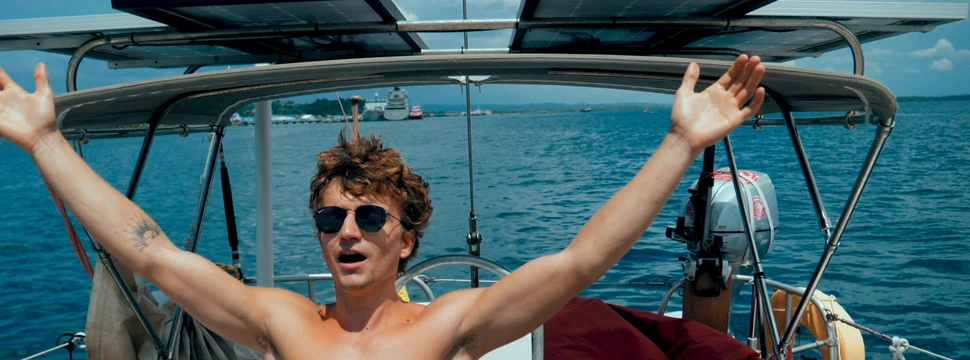 Junge auf einem Boot reißt die Arme in die Luft