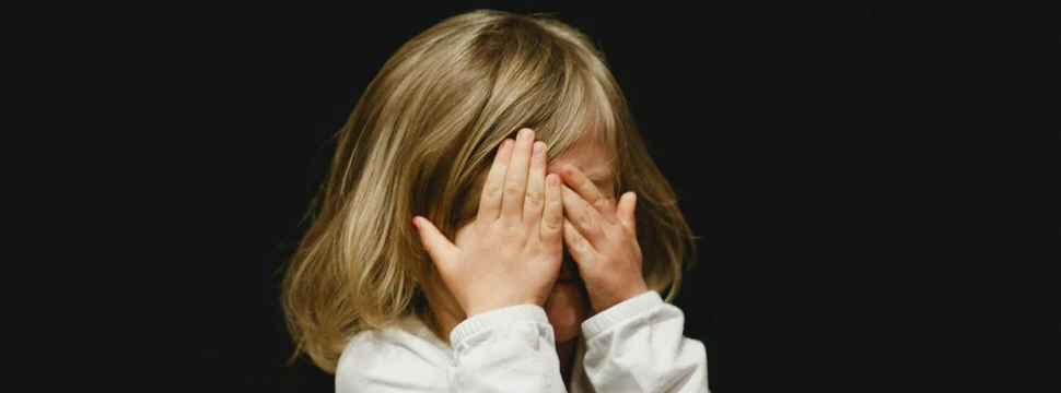 Mädchen hält sich die Hände vors Gesicht