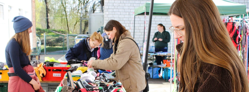 Menschen stöbern an einem Flohmarktstand mit Hunde Geschirren