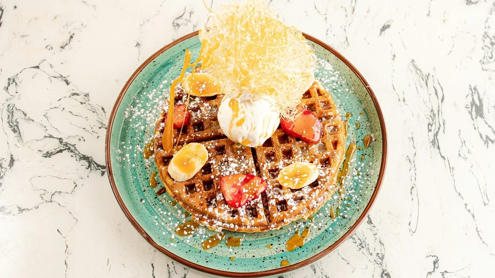 Eine Waffel mit Früchten, Eis und Puderzucker