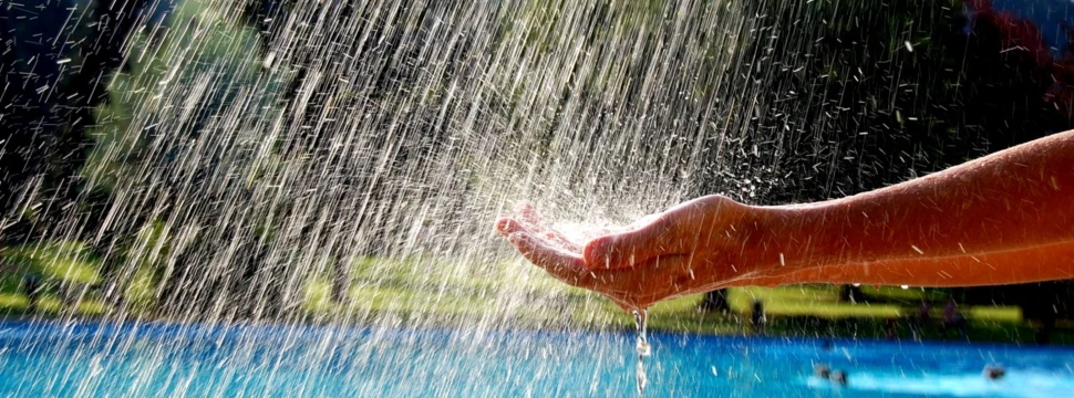 Hand unter einer Fontäne im Freibad