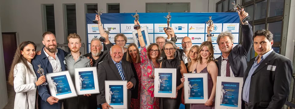 Die Menschen aus den ausgezeichneten Betrieben der siebten Auflage der Verleihung auf dem roten Teppich vor der Wand der Sponsoren der Veranstaltung