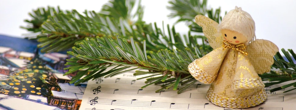 Weihnachtliche Deko auf einem Tisch, unter der sich Noten für ein Lied befinden