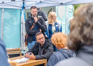 OB Yilmaz beim Austausch mit Menschen vor Ort während seiner Tour mit dem Tiny-Rathaus im Hintergrund