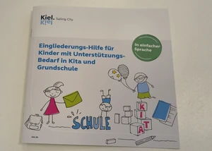 Ein Infomagazin, auf dessen Front "Eingliederungs-Hilfe für Kinder mit Unterstützungs-Bedarf in Kita und Grundschule" steht