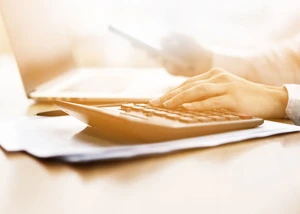 Hand liegt auf einem Taschenrechner, Bild in Sephia-Färbung