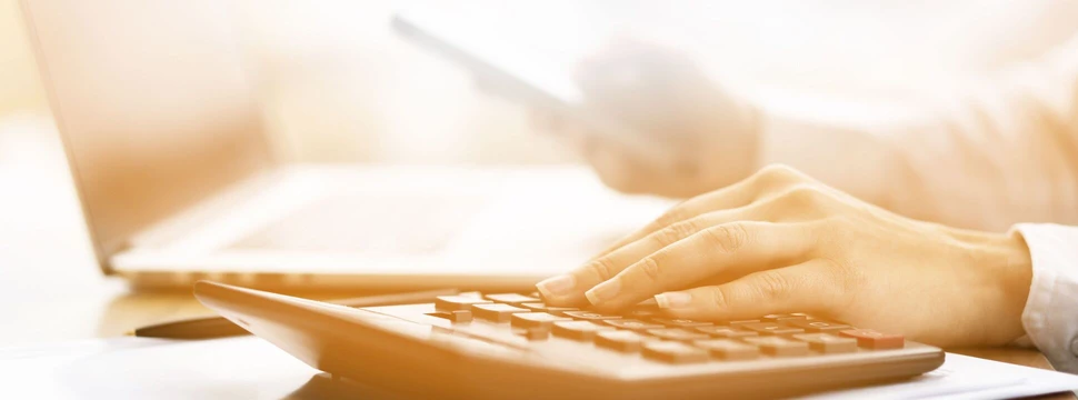 Hand liegt auf einem Taschenrechner, Bild in Sephia-Färbung