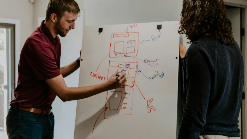 Mann bespricht Konzept am Whiteboard mit einer anderen Frau
