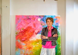 Eine Künstlerin vor einem ihrer Bilder in einem Raum mit hohen Decken