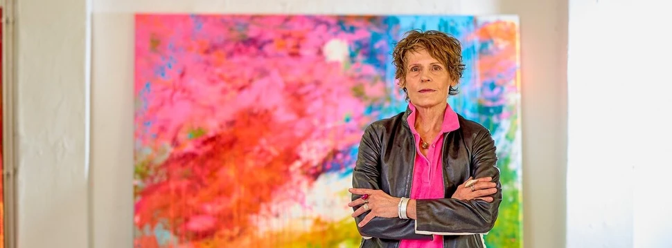 Eine Künstlerin vor einem ihrer Bilder in einem Raum mit hohen Decken