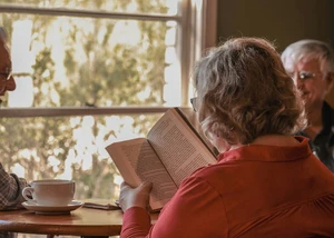 Eine Frau an einem Tisch beim Lesen eines Buches