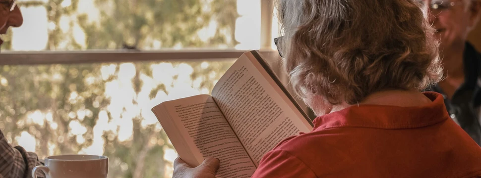 Eine Frau an einem Tisch beim Lesen eines Buches