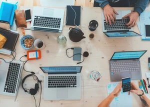 Auf einem Tisch liegen Laptops, Handys und Kabel