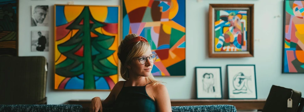 eine Frau sitzt in einem kunstvoll eingerichteten Wohnzimmer