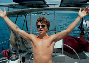 Junge auf einem Boot reißt die Arme in die Luft