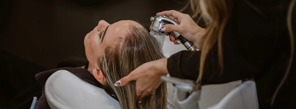 Eine Frau, die sich von einer Frau die Haare waschen
