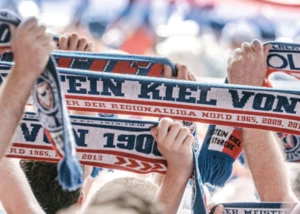 Fans mit dem Vereinsschal von Holstein Kiel Menschen mit Fanschals in der Hand, auf denen Holstein Kiel steht