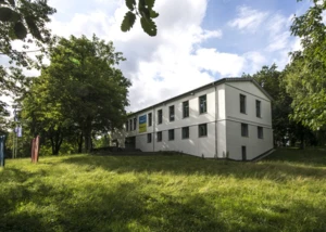 Ein weißes Gebäude, dass das Gebäude des Theaters im Werftpark ist. Hier von außen betrachtet