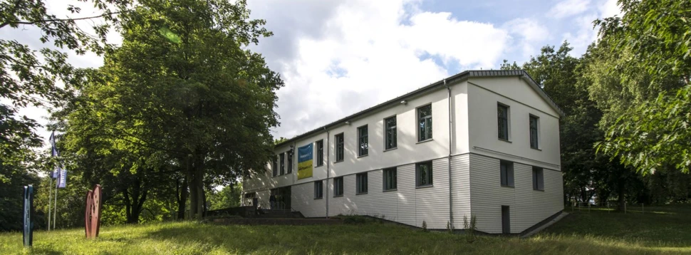 Ein weißes Gebäude, dass das Gebäude des Theaters im Werftpark ist. Hier von außen betrachtet