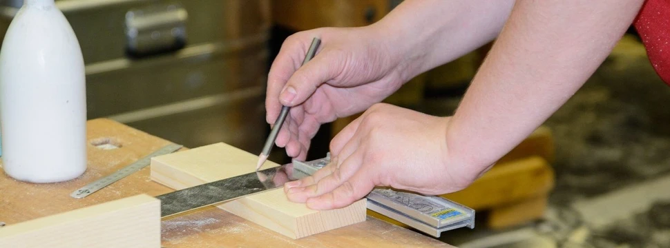 Ein Tischler zeichnet auf Holzblock an