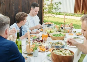 Mehrere Menschen, die gemeinsam an einem Tisch sitzen, auf dem sich verschiedene Speisen befinden