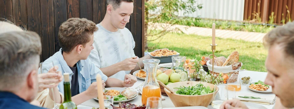 Mehrere Menschen, die gemeinsam an einem Tisch sitzen, auf dem sich verschiedene Speisen befinden