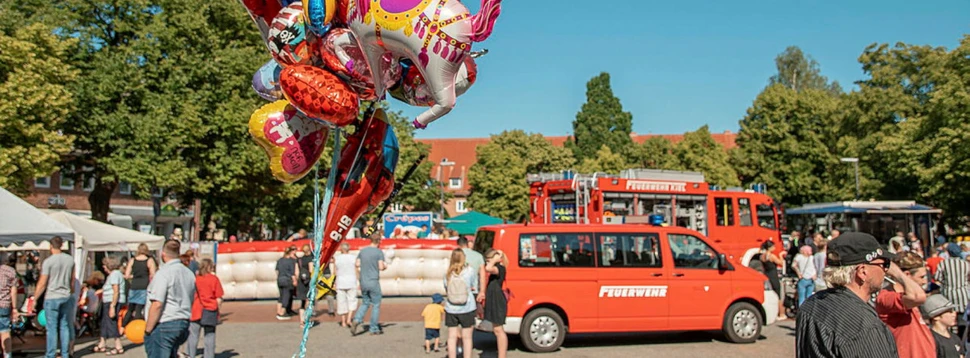 Ein Stadtteilfest während der Kieler Woche mit Luftballons, vielen Menschen und bunten Autos