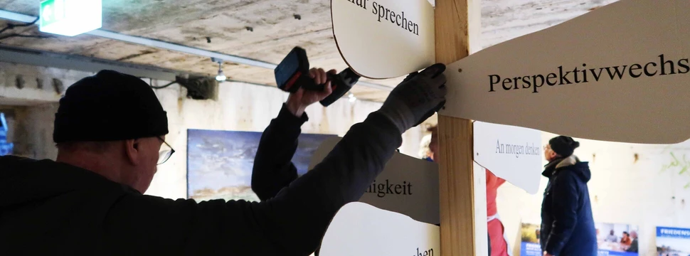 Mehrere Menschen, die in einem ehemaligen Bunker in Kiel an einer Ausstellungseröffnung arbeiten