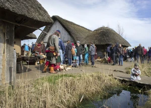 Ein Haus des Wikingermuseums Haitabu in Schleswig mit Menschen davor