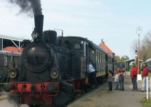 Ein Dampfzug mit Dampflok im Bahnhof Schönberger Strand, in den Menschen zusteigen