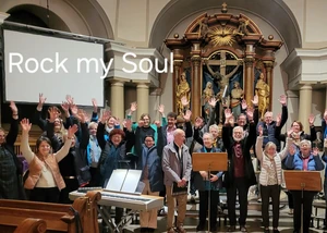 eine Menschengruppe steht in einer Kirche und hebt die Hände in die Luft