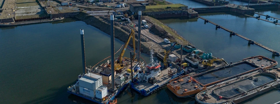 Ein Schiff vor einer Schleuse mit Containern im Hintergrund