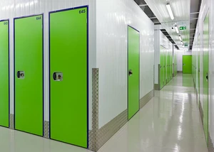 Ein Gebäude mit vielen Lagerräumen Grüne Türen in einem langen Flur mit Lampen an der Decke