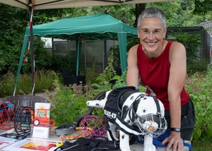 Ute Kleinschirkes geht ehrenamtlich mit Tierheimhunden Gassi Frau mit Hund an einem Tisch mit Maulkörben, dahinter ein Pavillon