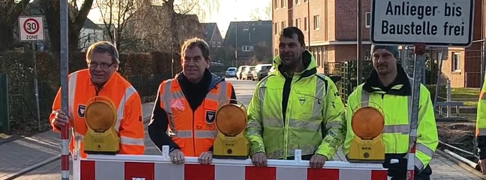 Mehrere Menschen in Warnwesten hinter einer Absperrbarke