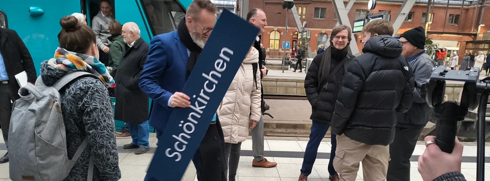 Der Wirtschaftsminister von Schleswig-Holstein mit einem Schild in der Hand, auf dem "Schönkirchen" steht