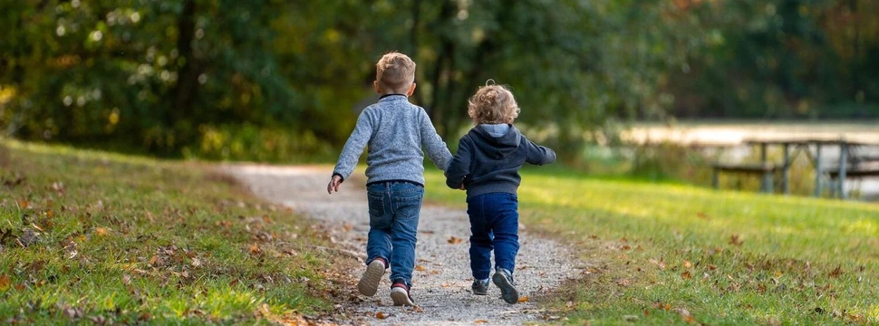 Kinder laufen auf einem Waldweg Zwei kleine Kinder laufen Hand in Hand Kinder auf einem Parkweg