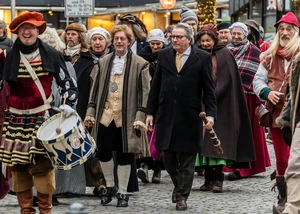 Mehrere Menschen in mittelalterlicher Kleidung, die an einem Umzug in der Kieler Innenstadt teilnehmen