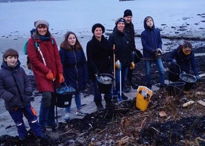 Mehrere Menschen, die zusammen an einem Strand Müll gesammelt haben