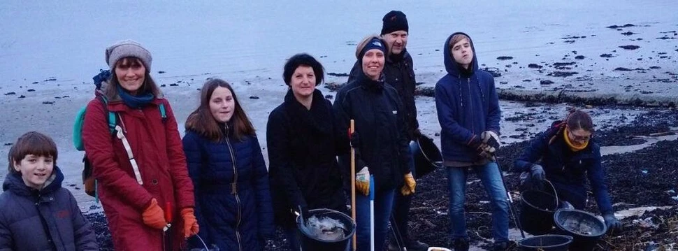 Mehrere Menschen, die zusammen an einem Strand Müll gesammelt haben