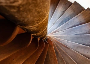 Spiralförmige Holztreppe mit warmer Beleuchtung und sichtbarer Holzmaserung