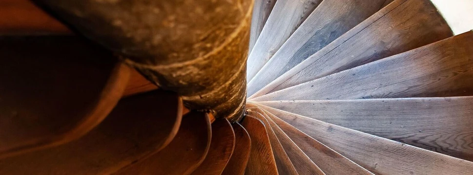 Spiralförmige Holztreppe mit warmer Beleuchtung und sichtbarer Holzmaserung