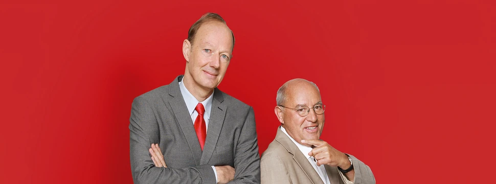 Gregor Gysi und Martin Sonneborn stehen nebeneinander vor einem rotem Hintergrund