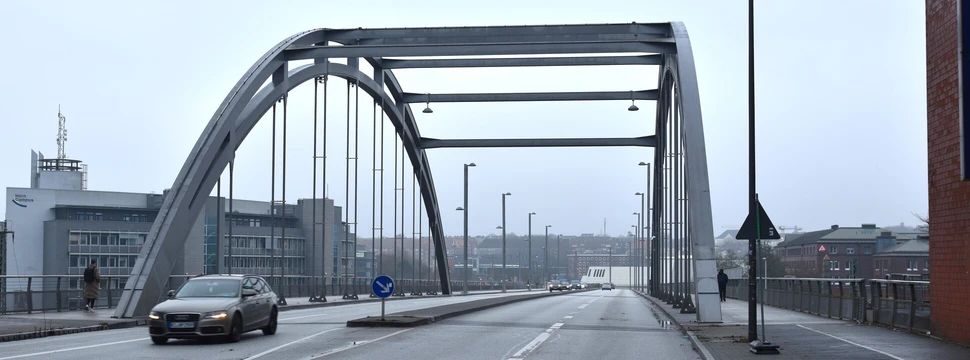 Eine Brücke in Kiel über die ein Auto fährt und bei der im Hintergrund Häuser zu sehen sind