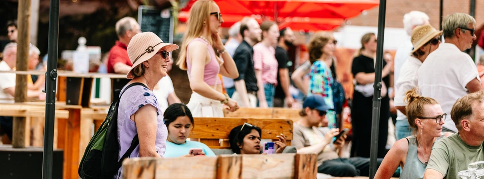 Mehrere Menschen, die auf Bänken sitzend die Kieler Woche genießen