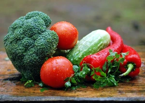 Buntes Arrangement aus frischem Gemüse auf einem Holztisch. Frisches Gemüse mit Brokkoli, Tomaten, Gurke, Paprika und Petersilie auf Holzunterlage.