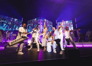 Mehrere Menschen auf einer Bühne, die Mikrophone in ihrer Hand halten